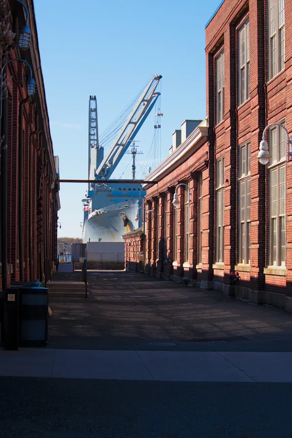 Ship at the Philadelphia Shipyard between brick buildings.