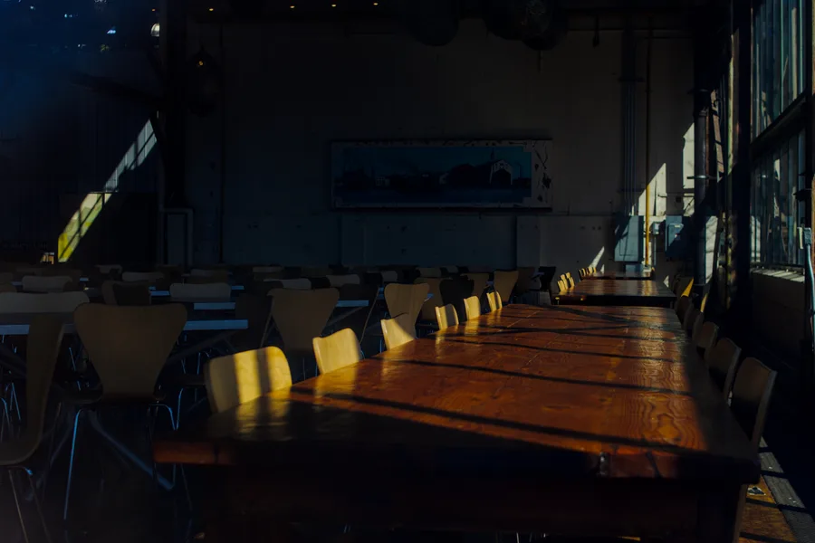 Cafeteria seating with light shining through the windows onto the tables.